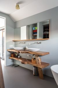 De gietvloer, de wanden en het spanplafond zijn strak, de meubelelementen hebben juist natuurlijke vormen