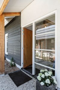 De voordeur bevindt zich aan de zijkant - daar waar de gevelbekleding deels met wit stucwerk is