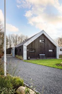 Vanaf de weg heeft de woning de basale vorm van een schuur