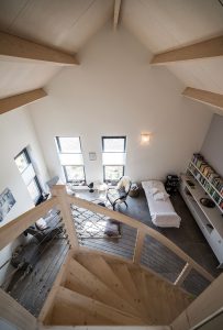 De serene praktijkruimte met houten trap naar de vide